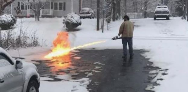 Man uses flame thrower to clear the driveway